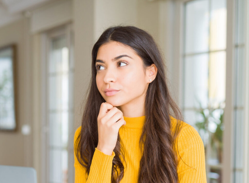 Woman looking thoughtful while considering pregnancy and abortion information from PRC Grand Rapids.