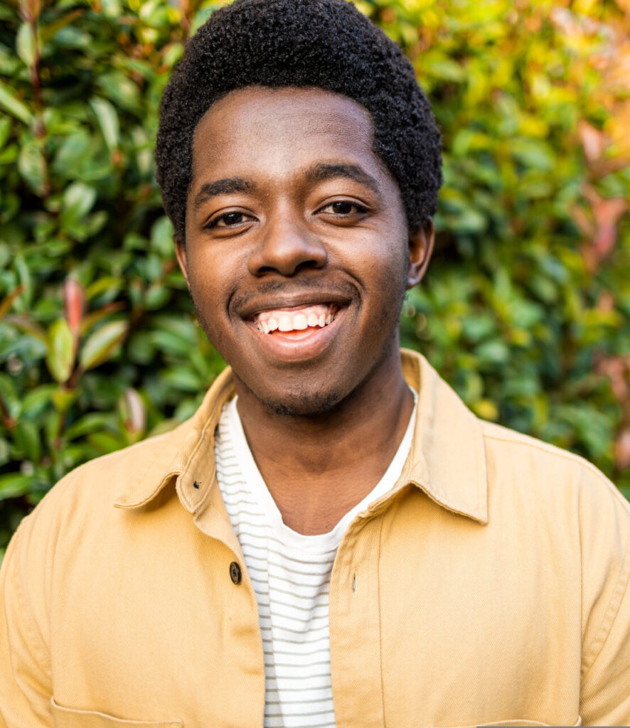 Man smiling outdoors while supporting a partner through a pregnancy journey.