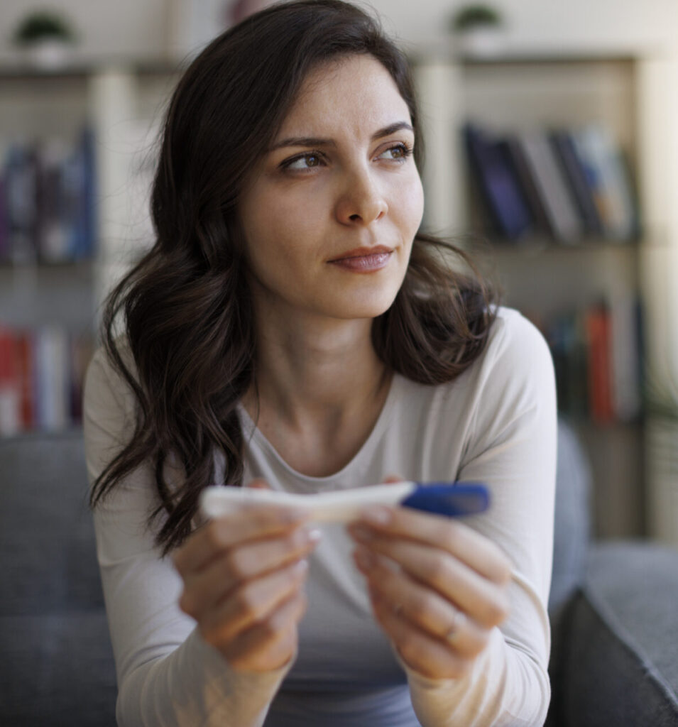 Woman holding a pregnancy test and reviewing results during a confidential consultation.