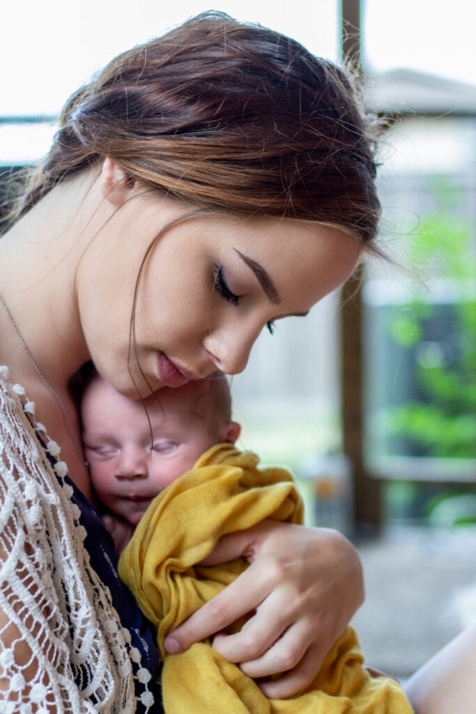 Mother holding her newborn baby, smiling at home.